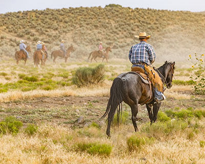 Ranchers on horseback crossing open rangeland