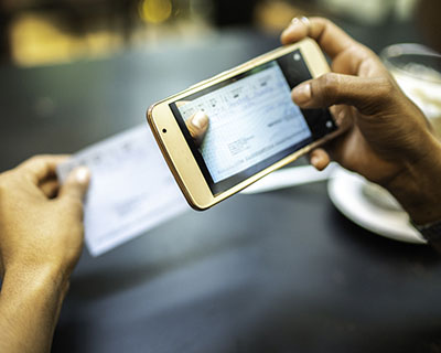 Person using a smartphone to photograph a check