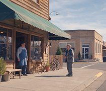 People talking outside businesses on a small-town Main Street