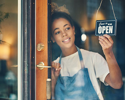 Small-business owner turning an open sign at a storefront